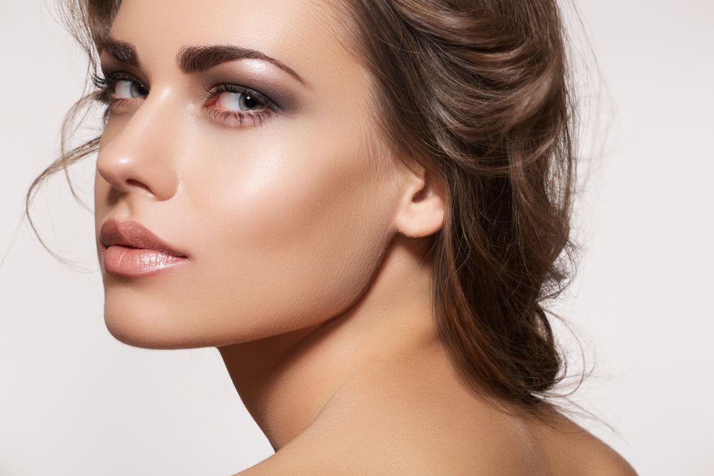 A beautiful, young woman with pinned-up brunette hair looks seductively over her shoulder.