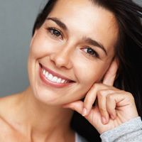 Una hermosa mujer morena apoya su cabeza en sus dedos extendidos.